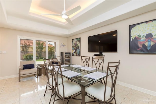 dining room with a raised ceiling, light tile patterned flooring, baseboards, and ceiling fan