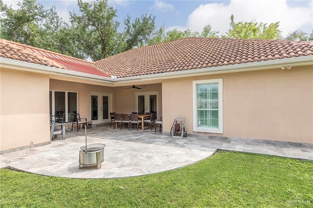 rear view of house featuring french doors, stucco siding, a ceiling fan, a lawn, and a tiled roof