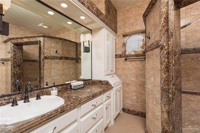 full bath with recessed lighting, vanity, a tile shower, tile walls, and tile patterned floors