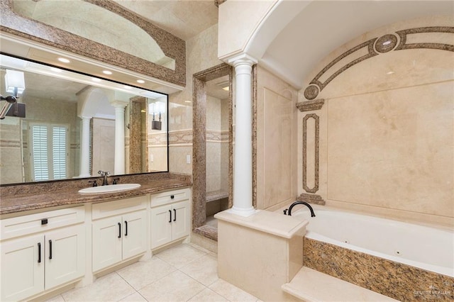 bathroom with decorative columns, tile walls, a whirlpool tub, vanity, and tile patterned flooring