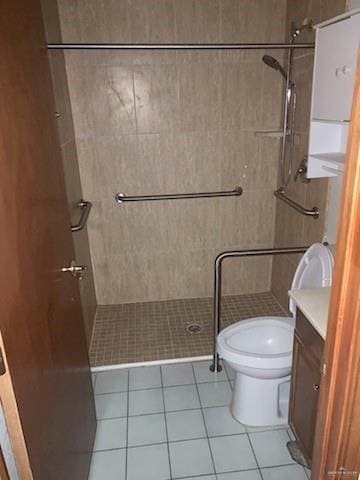 bathroom featuring tile patterned flooring, vanity, toilet, and tiled shower