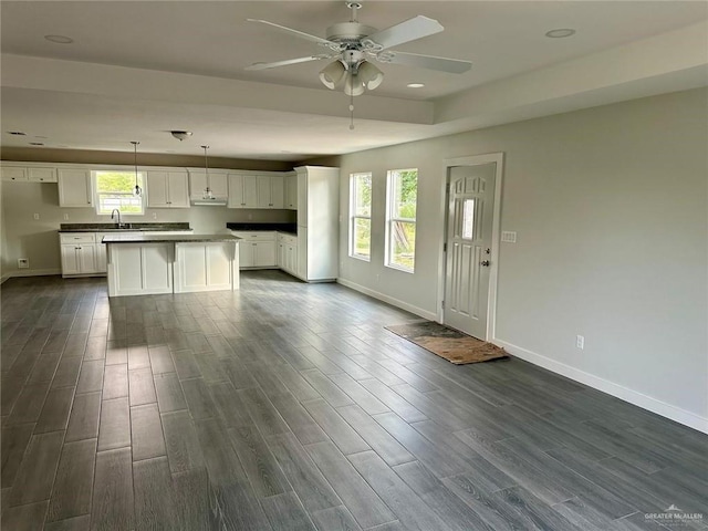 kitchen with white cabinetry, sink, a kitchen island, and hanging light fixtures