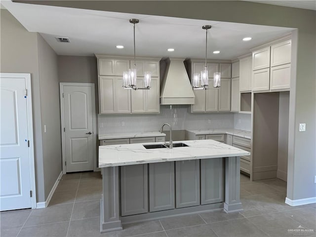 12711 N 37th Ln, Mcallen, TX 78504 - kitchen with premium range hood, a chandelier, a center island with sink, tasteful backsplash, and light tile patterned flooring