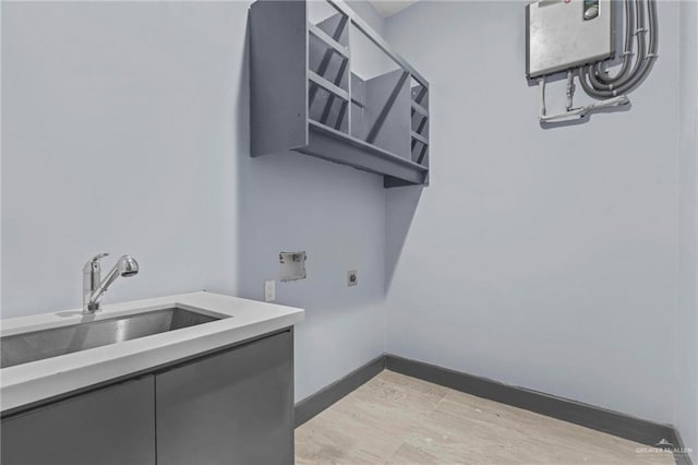 clothes washing area featuring sink, light hardwood / wood-style flooring, and electric dryer hookup