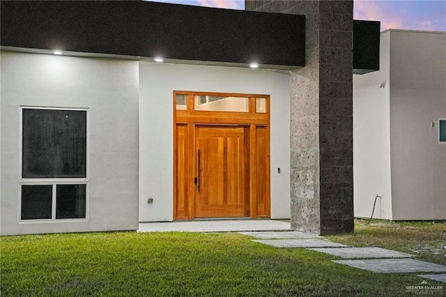 exterior entry at dusk with a lawn