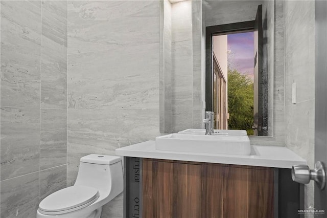 bathroom with vanity, tile walls, and toilet