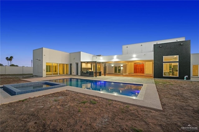 pool at dusk with an in ground hot tub and a patio