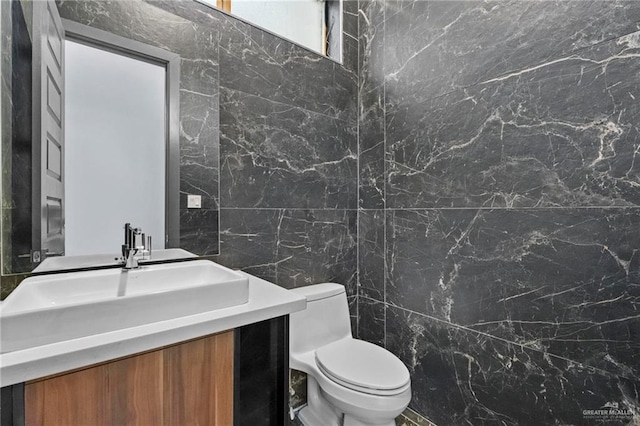 bathroom with vanity, toilet, and tile walls