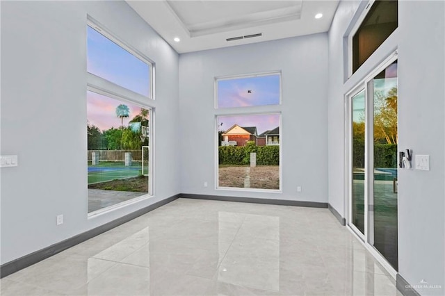 empty room featuring a tray ceiling, a towering ceiling, and a wealth of natural light