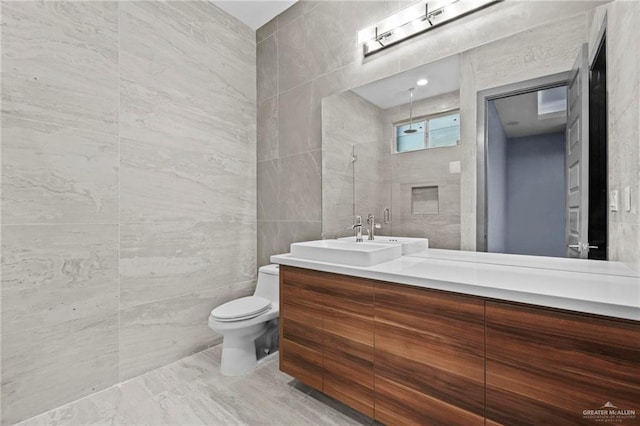 bathroom with vanity, toilet, and tile walls