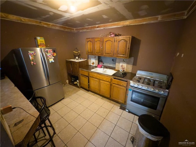 4810 Amber St, Mission, TX 78574 - kitchen featuring stainless steel appliances, light tile patterned flooring, brown cabinetry, and a sink