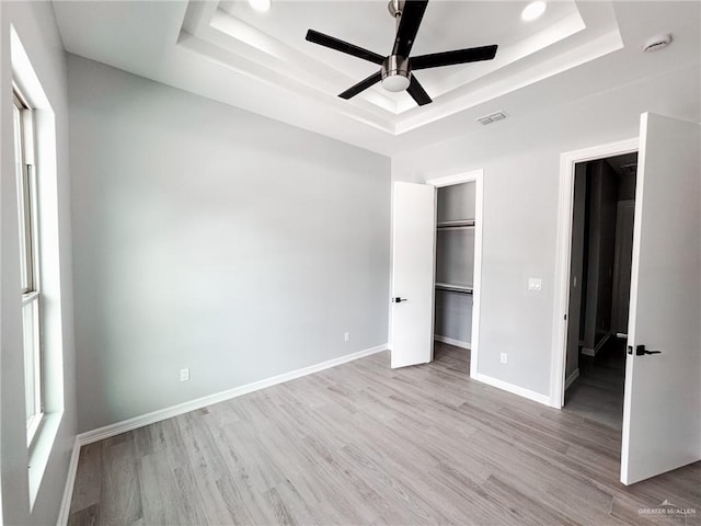 607 N 9th St, Alamo, TX 78516 - unfurnished bedroom featuring a tray ceiling, light wood-type flooring, ceiling fan, a walk in closet, and a closet