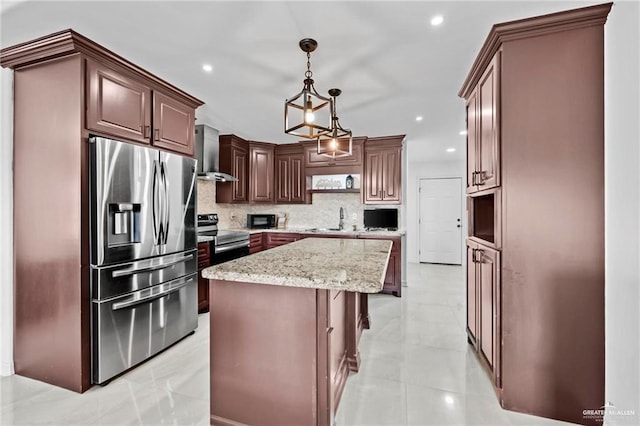 kitchen featuring decorative backsplash, appliances with stainless steel finishes, wall chimney exhaust hood, a kitchen island, and hanging light fixtures