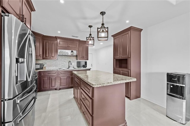 kitchen with a center island, sink, hanging light fixtures, stainless steel fridge, and decorative backsplash