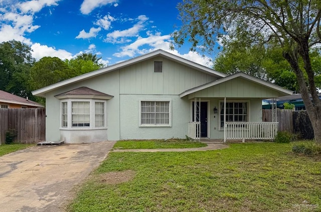 view of front of property featuring covered porch, fence, a front yard, and driveway