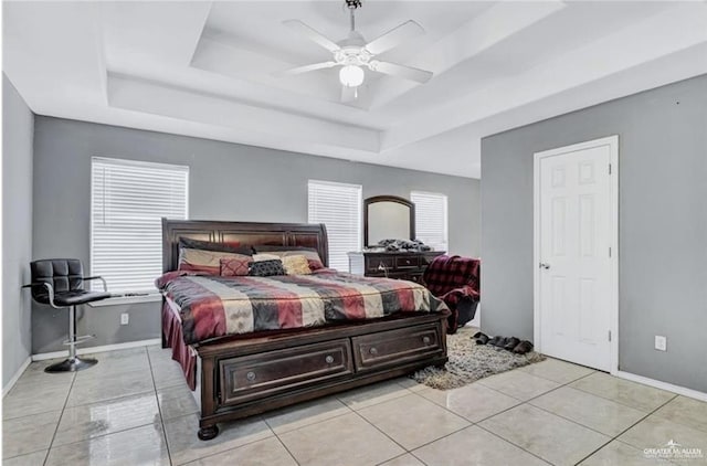 tiled bedroom featuring baseboards, a tray ceiling, and a ceiling fan