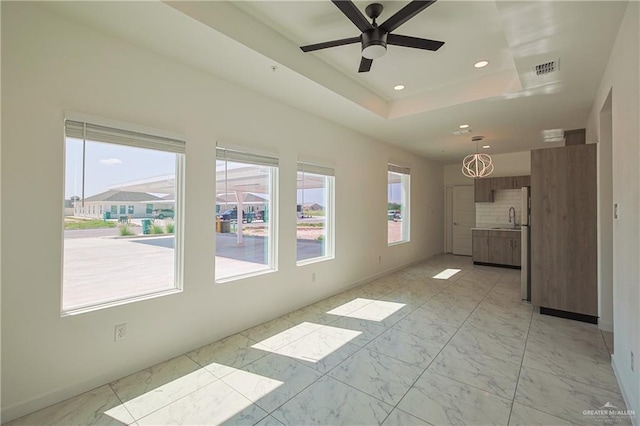 unfurnished living room featuring recessed lighting, a sink, baseboards, marble finish floor, and a raised ceiling