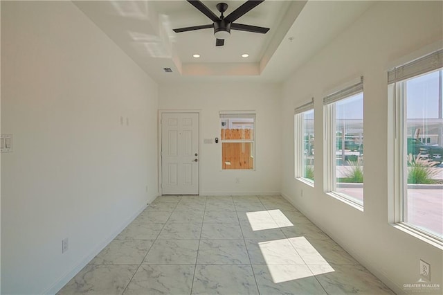 empty room with baseboards, a raised ceiling, a ceiling fan, marble finish floor, and recessed lighting