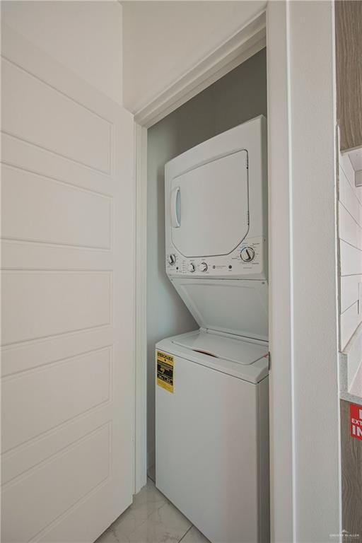 laundry room with marble finish floor, stacked washing maching and dryer, and laundry area