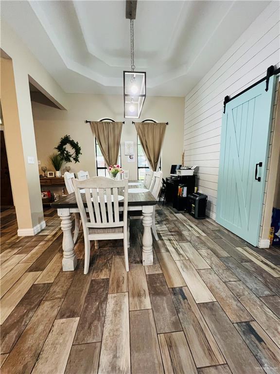 2031 Pena St, Mission, TX 78572 - dining space with a barn door, a raised ceiling, dark wood-type flooring, and wood walls