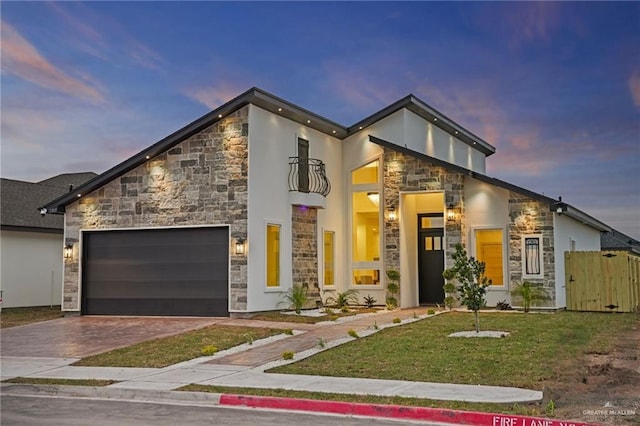 contemporary house featuring decorative driveway, stucco siding, fence, a garage, and stone siding