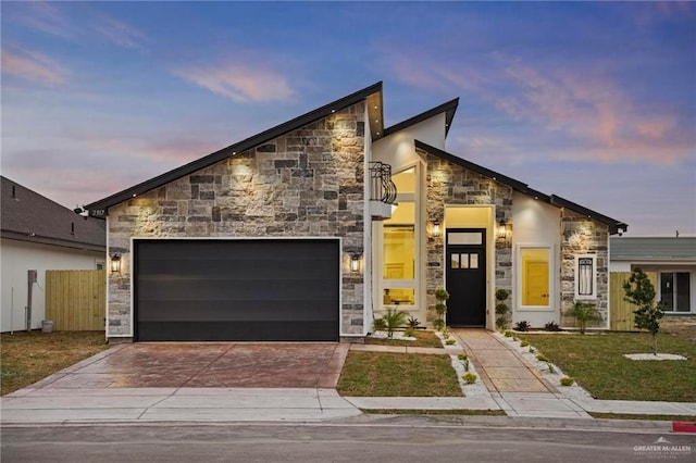 modern home featuring an attached garage, stone siding, fence, and decorative driveway