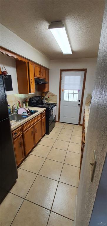 1319 Sago Palm St, Alamo, TX 78516 - kitchen with black appliances, under cabinet range hood, brown cabinets, light countertops, and a textured ceiling