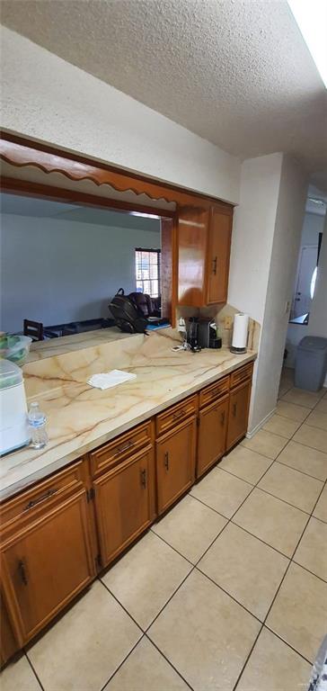 1319 Sago Palm St, Alamo, TX 78516 - kitchen featuring brown cabinetry, light countertops, a textured ceiling, and light tile patterned flooring