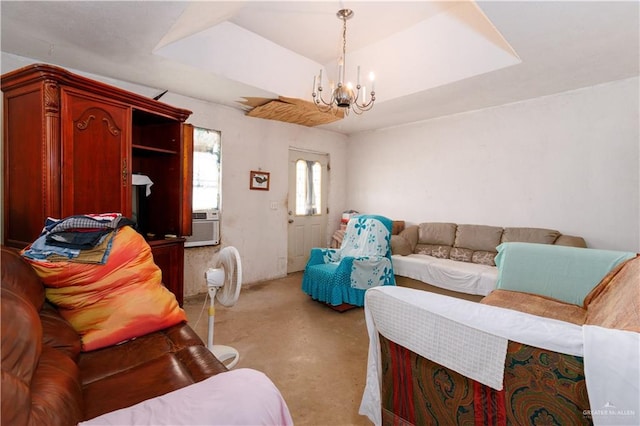 living room with a tray ceiling, cooling unit, and a chandelier