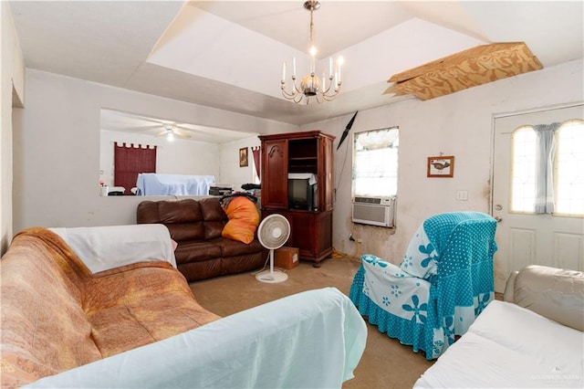 carpeted living room with cooling unit, ceiling fan with notable chandelier, a healthy amount of sunlight, and a tray ceiling