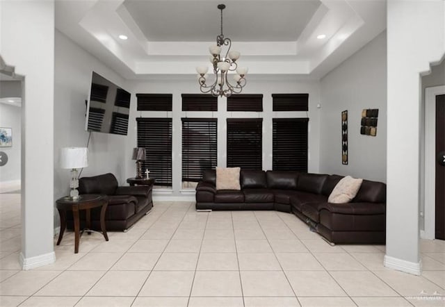 living room featuring a raised ceiling, a notable chandelier, baseboards, and light tile patterned floors