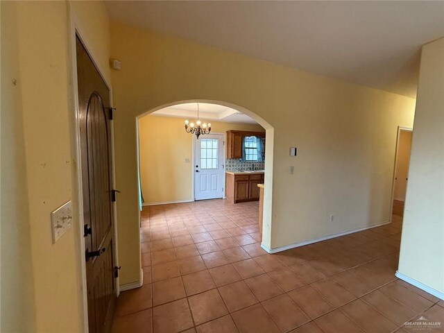 1008 Ivory Ave, Rio Grande City, TX 78582 - spare room with arched walkways, light tile patterned flooring, a chandelier, and baseboards