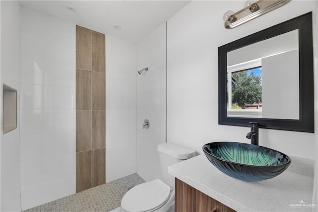 bathroom featuring vanity, toilet, and a tile shower