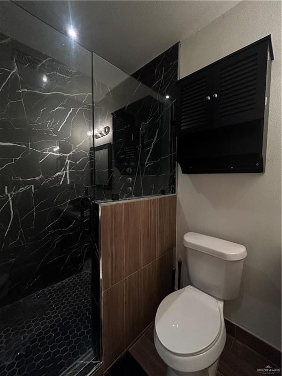 bathroom with a tile shower and toilet