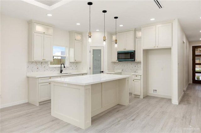 5204 Shalom Dr, Edinburg, TX 78539 - kitchen with black microwave, a sink, a center island, backsplash, and light wood-type flooring