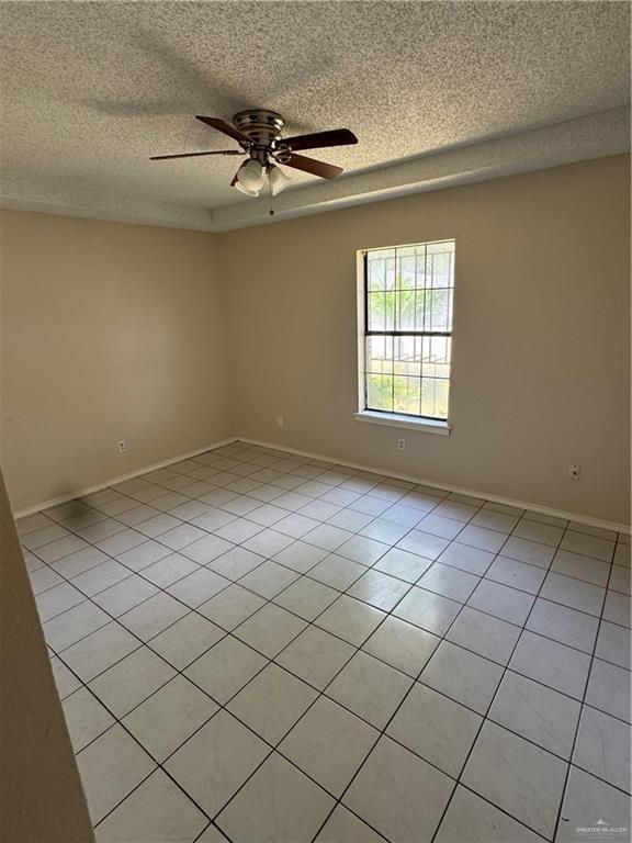 412 Silverado Dr E, Palmview, TX 78572 - empty room featuring a textured ceiling, ceiling fan, light tile patterned flooring, and baseboards