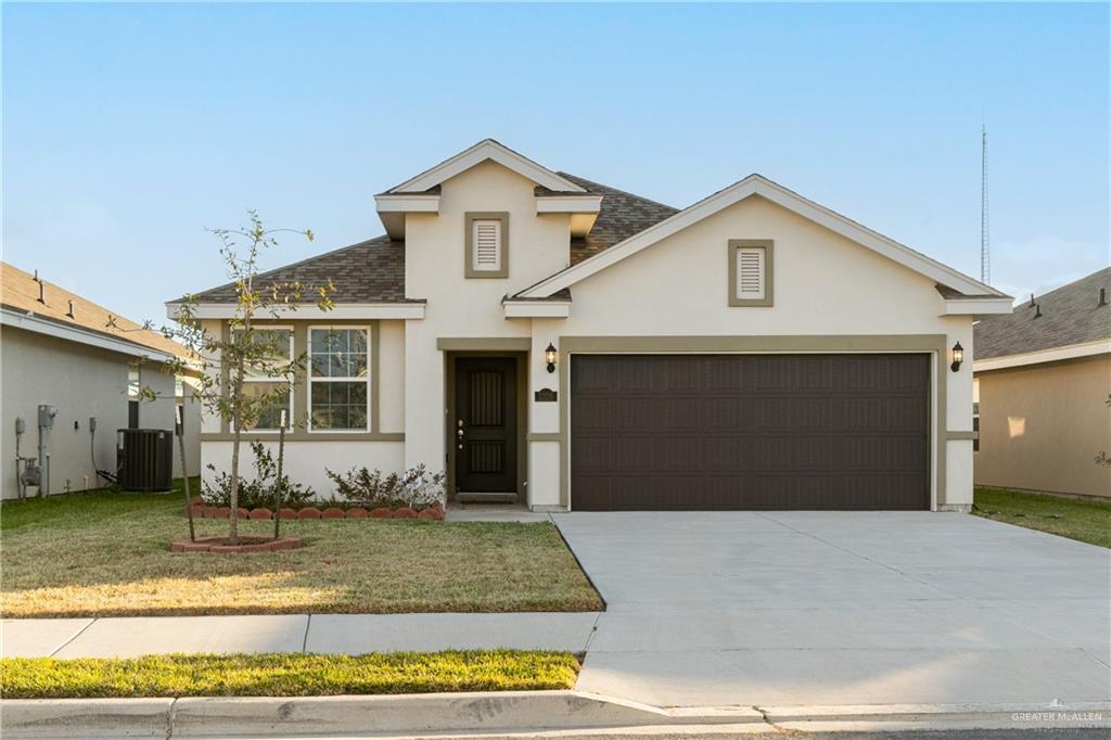traditional-style home featuring stucco siding, an attached garage, central AC unit, and driveway