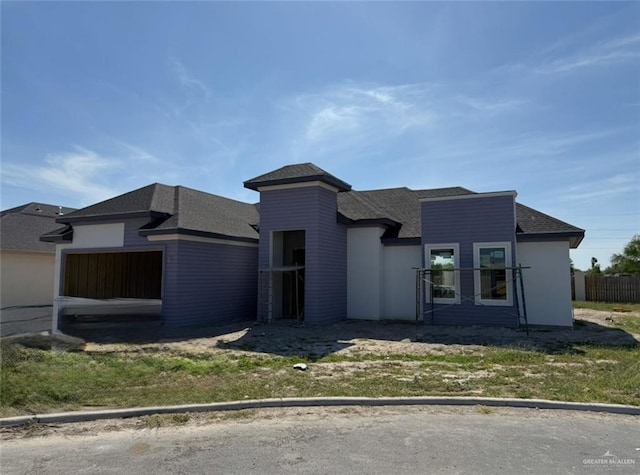 view of front of home featuring fence, a shingled roof, and a garage