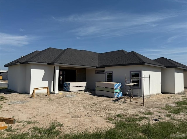 back of property featuring roof with shingles and stucco siding