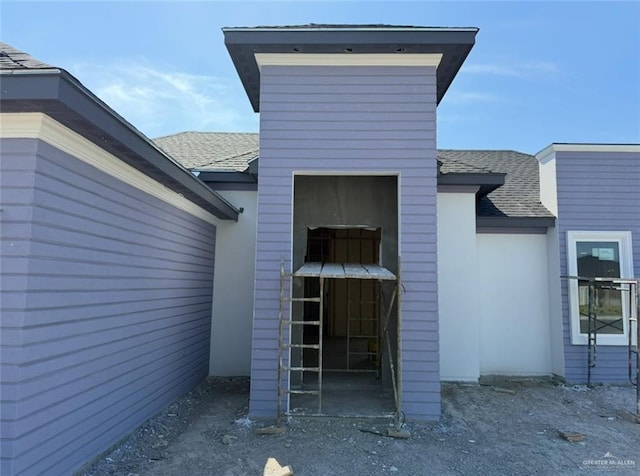 doorway to property featuring roof with shingles