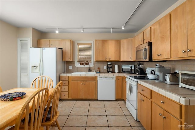 kitchen with light tile patterned floors, white appliances, tile countertops, and sink