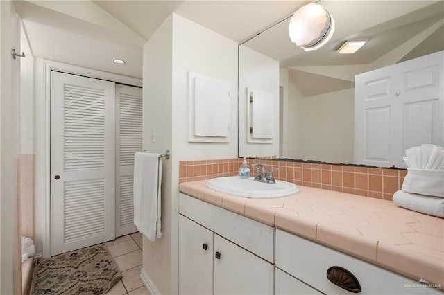 bathroom with tile patterned floors, vanity, lofted ceiling, and tasteful backsplash