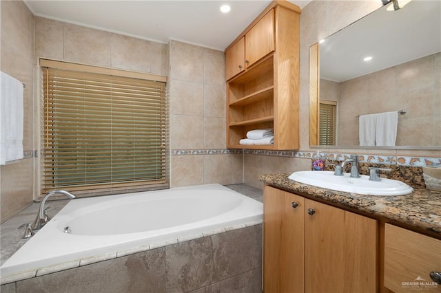 bathroom with vanity, tile walls, and tiled tub