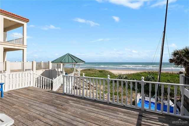 wooden deck with a water view and a beach view