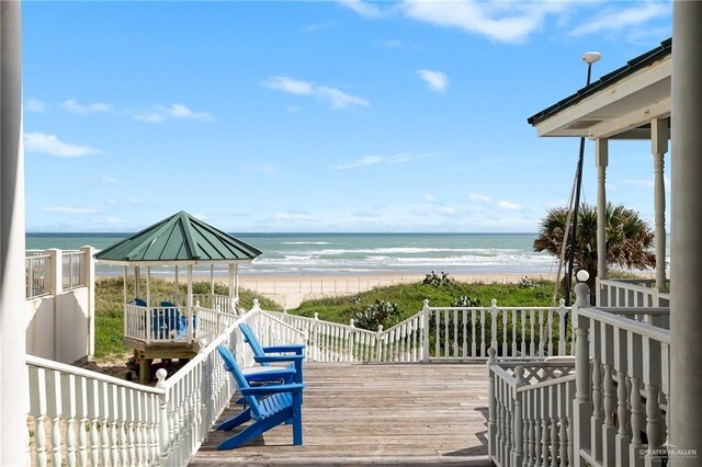 wooden terrace featuring a gazebo, a view of the beach, and a water view