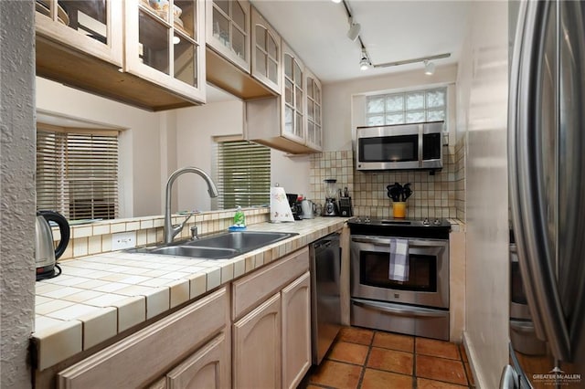 kitchen featuring tile counters, sink, decorative backsplash, light brown cabinetry, and appliances with stainless steel finishes