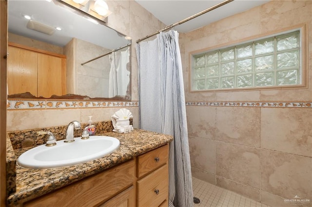 bathroom with a wealth of natural light, vanity, tile walls, and walk in shower