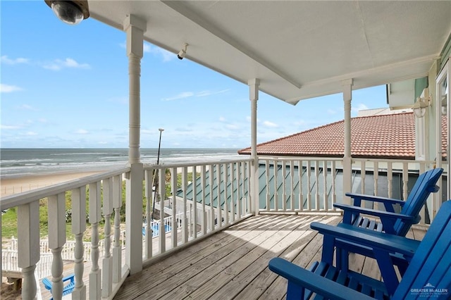 wooden terrace featuring a water view and a beach view