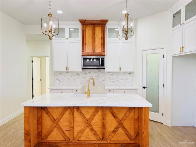 2125 Blue Sky Dr, Weslaco, TX 78599 - kitchen with a chandelier, stainless steel microwave, light wood-style floors, and backsplash