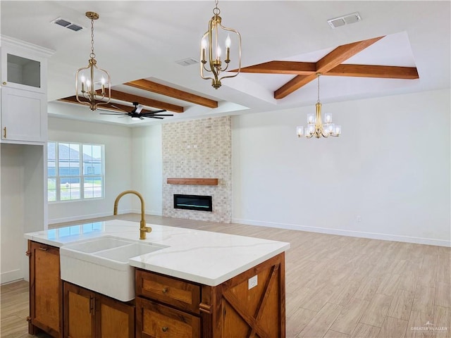2125 Blue Sky Dr, Weslaco, TX 78599 - kitchen with a chandelier, beam ceiling, a tiled fireplace, open floor plan, and light wood-style floors
